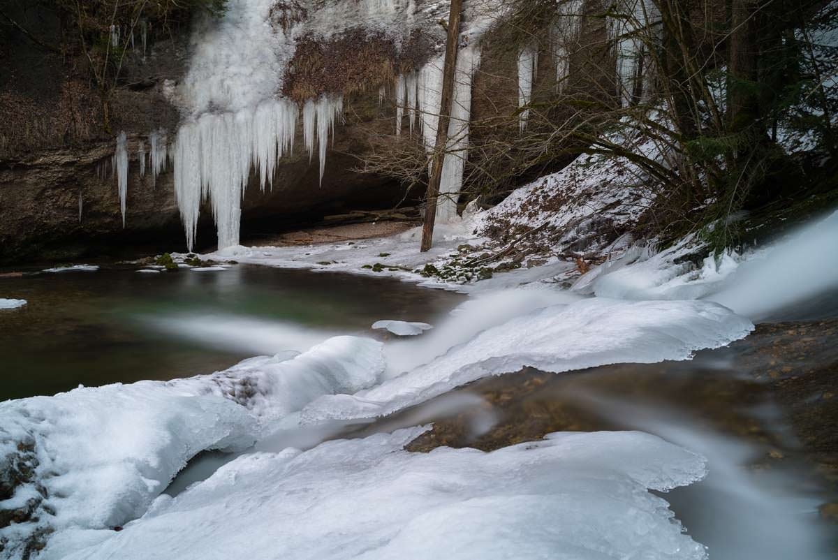 Zusammen mit dem Eisvorhang und dem smaragdgrünen Becken ergibt sich eine faszinierende Winterwelt. Gefrorener Wasserfall am Eissteg (Winter im Eistobel)