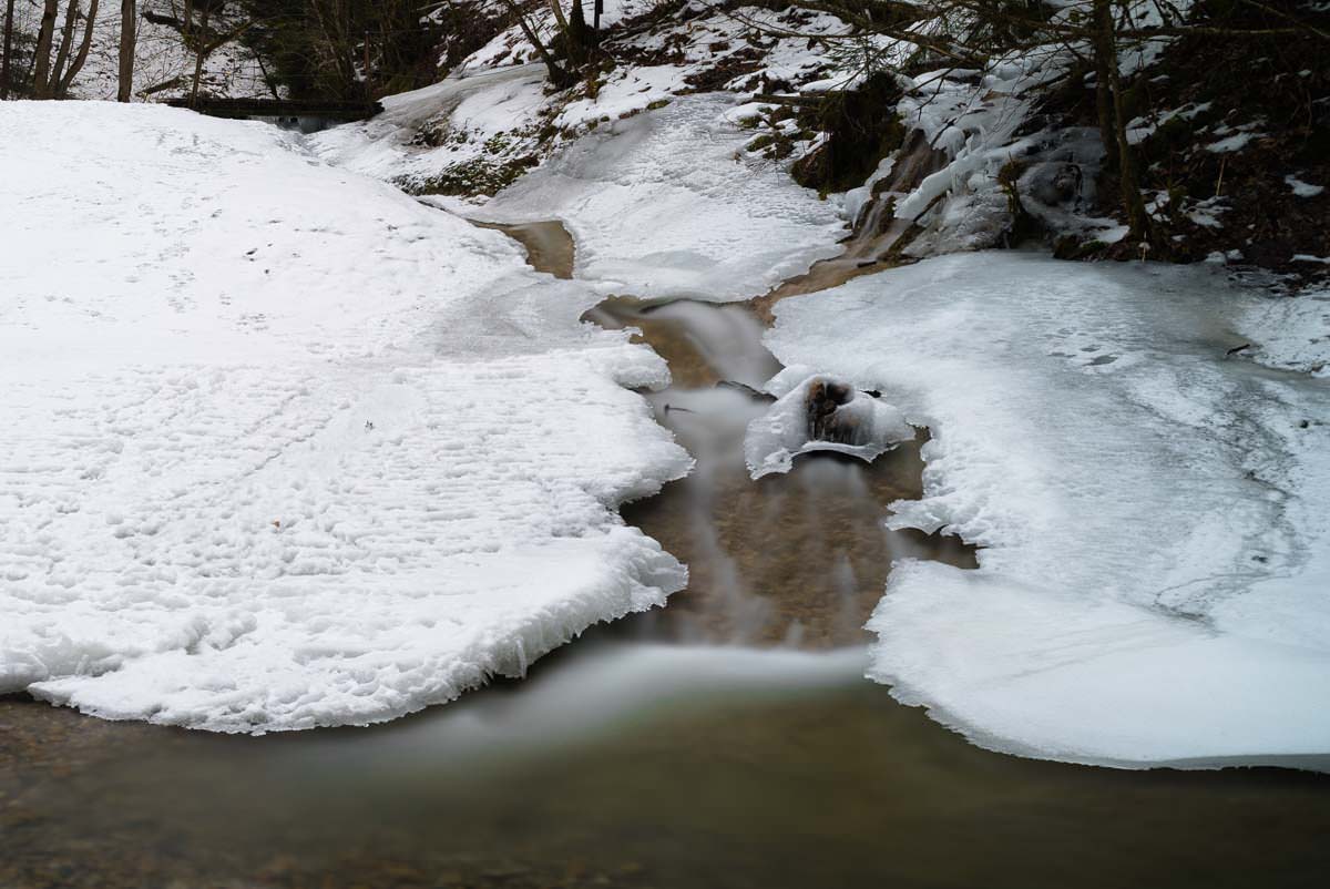 Fast vollständig gefrorener Wasserfall Gefrorener Wasserfall im Eistobel im Winter
