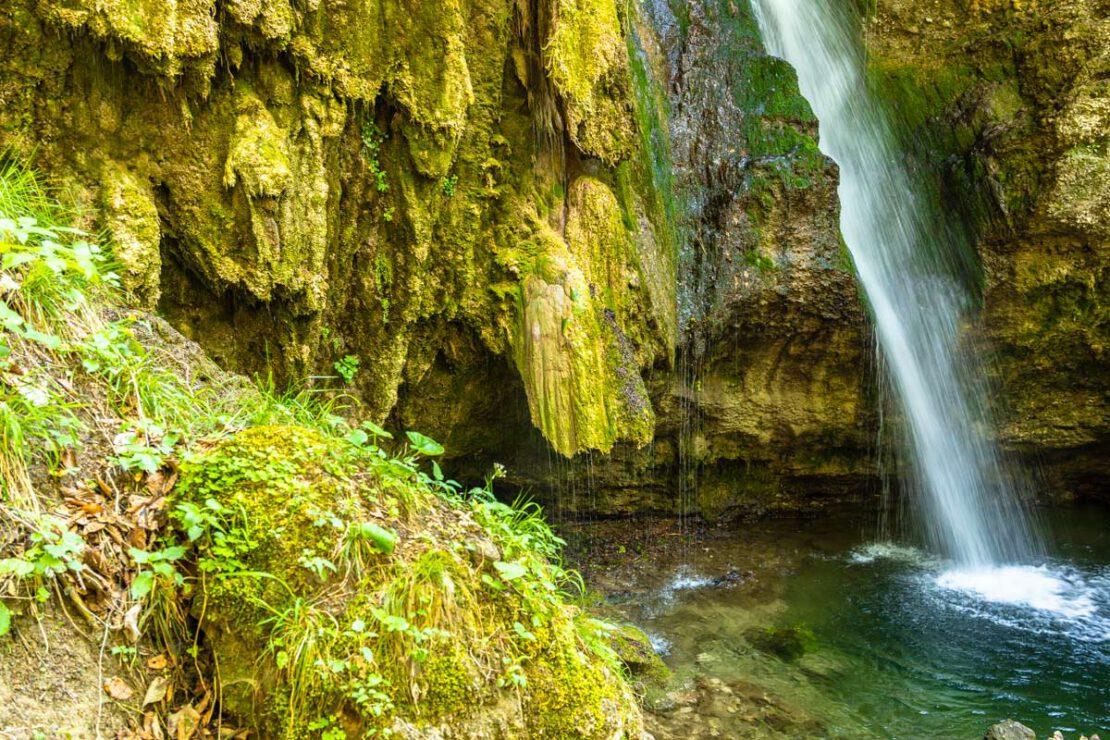 Der Hinanger Wasserfall fließt über Kalktuff und Moos in ein türkisgrünes Becken